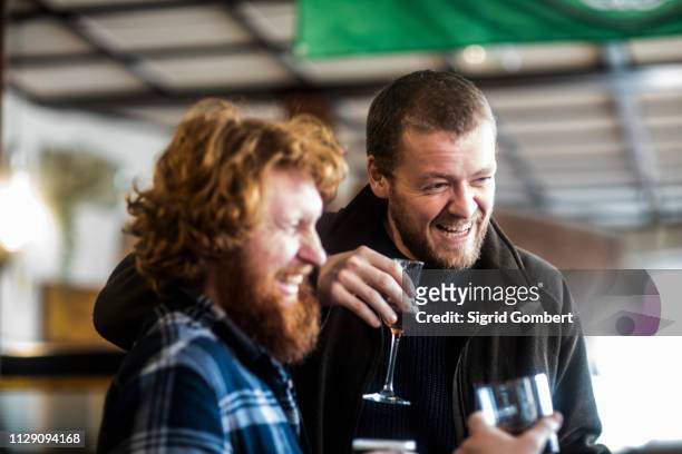 two male customers laughing in traditional irish public house - irische kultur stock-fotos und bilder