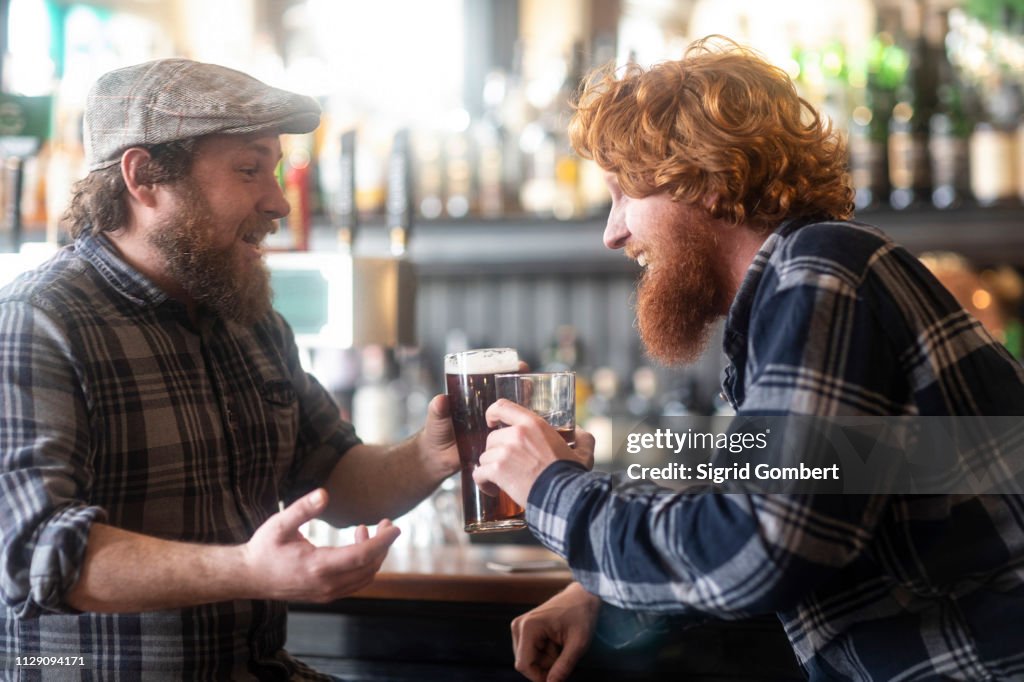 Two male customers making a toast in traditional Irish public house