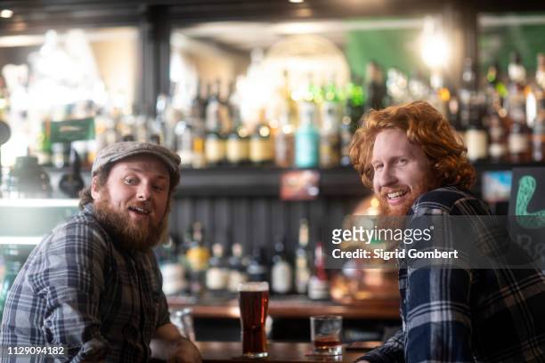 two male customers looking over their shoulders from bar in traditional irish public house - mates pub stock-fotos und bilder
