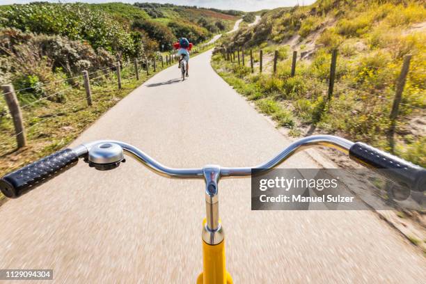 cycling along rural road between dunes near den haag, personal perspective, scheveningen, south holland, netherlands - fahrradlenker stock-fotos und bilder