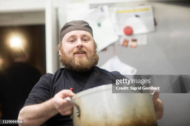 fast food worker carrying large pan in commercial kitchen, portrait - sigrid gombert stock-fotos und bilder