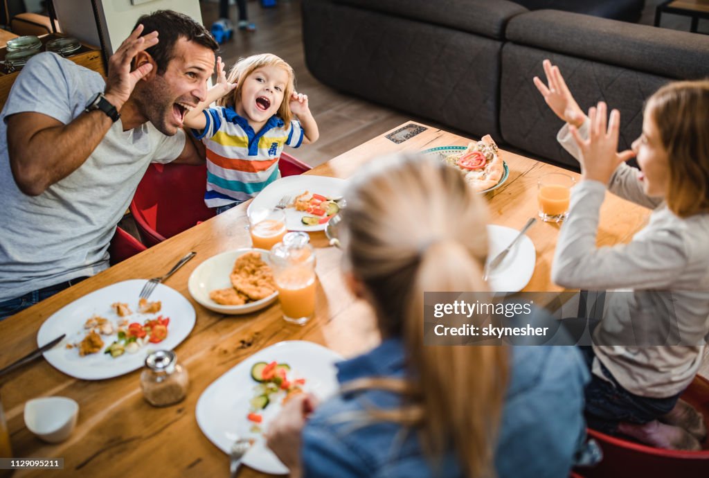 Glückliche Familie Grimassen während des Mittagessens am Esstisch.
