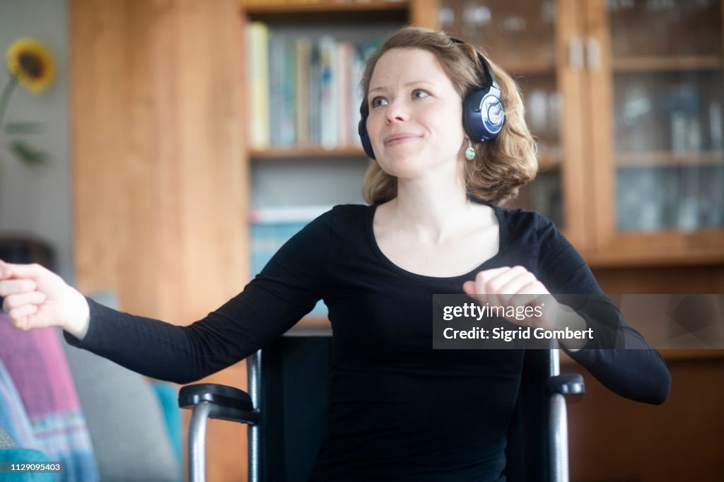 Woman in wheelchair dancing to music on headphones
