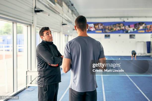 coach and runner speaking in indoor running track - sport coach united kingdom stock pictures, royalty-free photos & images