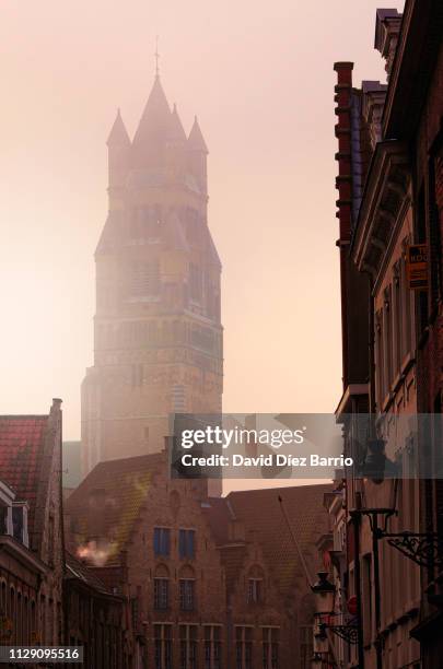tower of the sint-salvator cathedral in bruges seen from one of the city streets - amanecer ciudad foto e immagini stock