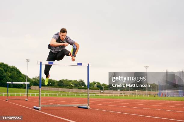athlete jumping over hurdle on running track - estadio de atletismo fotografías e imágenes de stock