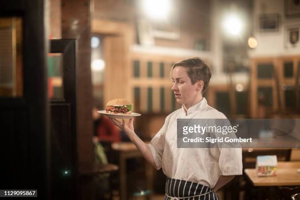 waitress serving plate of burger in gastro pub - gastro pub stock pictures, royalty-free photos & images