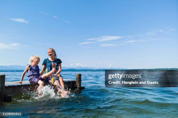 mother and daughter cooling feet in water, lake starnberg, bavaria, germany - starnberger see stock-fotos und bilder