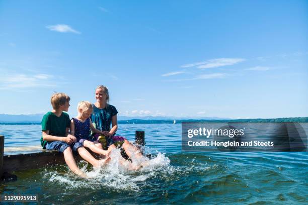 mother and children cooling feet in water, lake starnberg, bavaria, germany - starnberger see stock-fotos und bilder