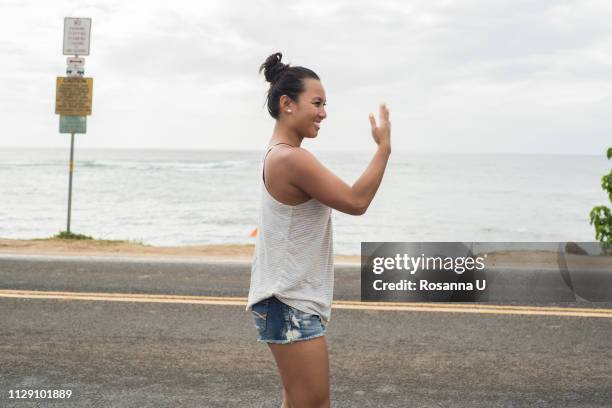 woman signalling on road by beach, haleiwa, oahu, hawaii - 招き寄せる ストックフォトと画像