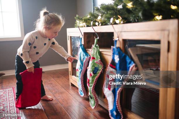 toddler girl hanging up christmas stockings - stocking tops stock-fotos und bilder