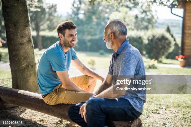 hijo adulto feliz hablando con su padre en el patio trasero. - yerno fotografías e imágenes de stock