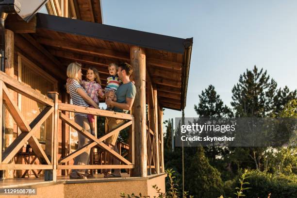 heureux parents et leurs petits enfants parler sur un balcon de leur chalet. - chalets photos et images de collection