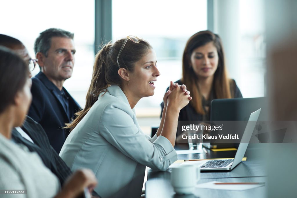Co-workers having meeting with laptop in conference room