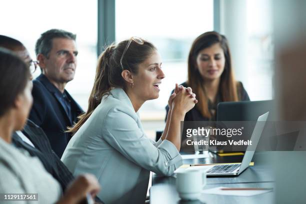 co-workers having meeting with laptop in conference room - men and women in a large group listening stock pictures, royalty-free photos & images