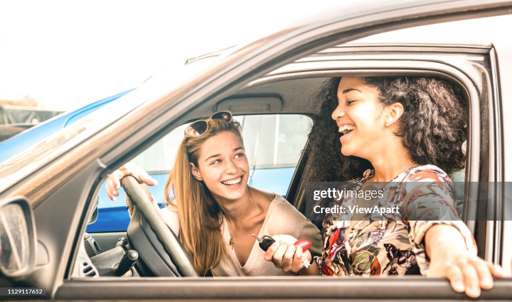 Young female best friends having fun at car roadtrip moment - Transportation concept and urban ordinary life with women girlfriends at happy travel vacation on the road - Bright azure filter