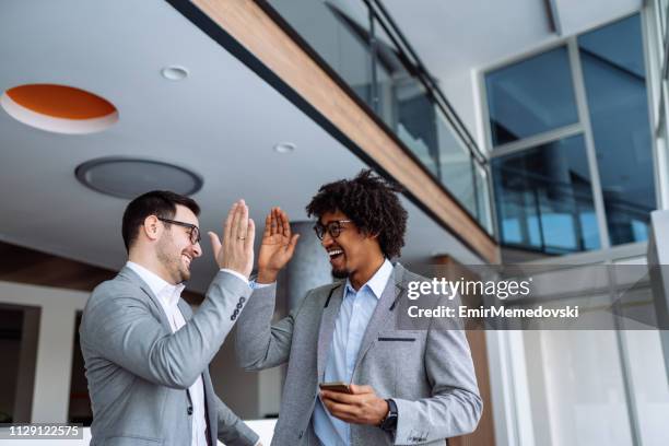 due uomini d'affari che si danno l'un l'altro high-five - team office high five foto e immagini stock