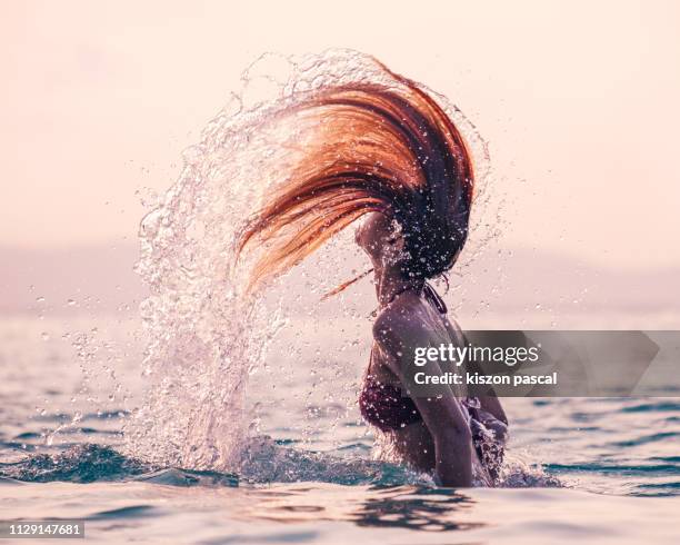 beautiful woman doing a spin with her hair in the ocean during sunset . - capelli onde foto e immagini stock