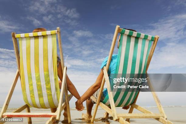 man and woman on beach in deckchairs - man on the beach relaxing in deckchair fotografías e imágenes de stock