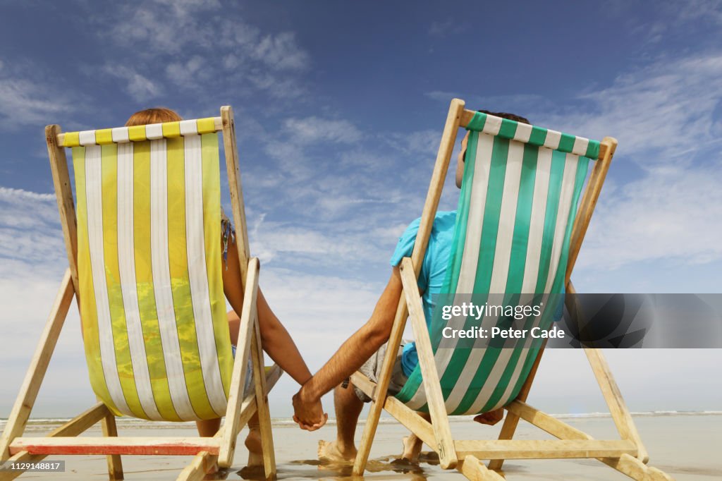 Man and woman on beach in deckchairs