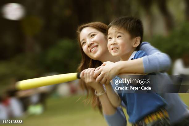 mother and son hitting ball with bat - baseball mom stock pictures, royalty-free photos & images