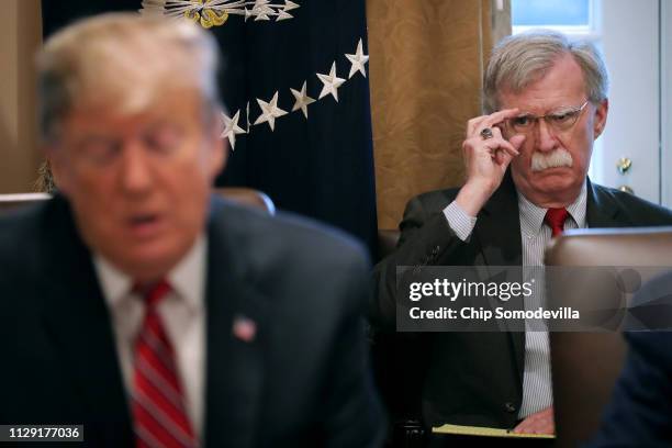 National Security Advisor John Bolton listens to U.S. President Donald Trump talk to reporters during a meeting of his cabinet in the Cabinet Room at...