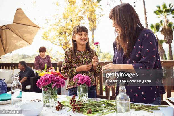 mother and daughter arranging flowers on table in backyard - los angeles garden party stock pictures, royalty-free photos & images