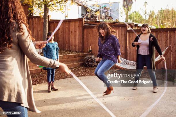 laughing woman performing double dutch jump rope in backyard - fitness or vitality or sport and women fotografías e imágenes de stock