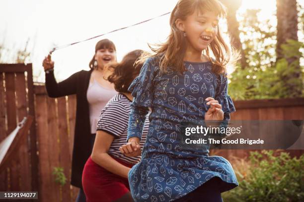 young girl jumping rope with friend in backyard - los angeles garden party stock pictures, royalty-free photos & images