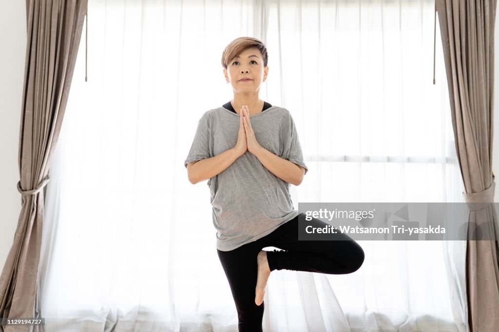 Thai middle-aged woman enjoys yoga at home
