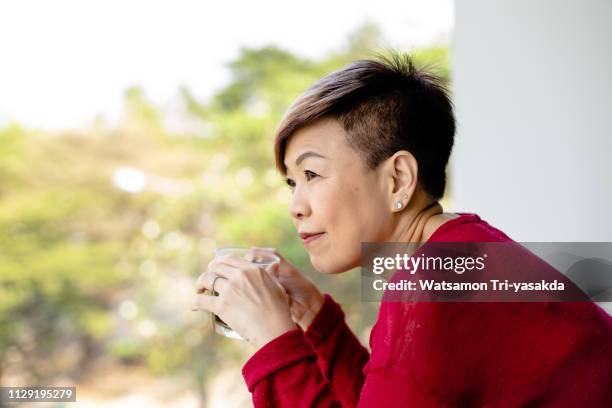 thai mature woman enjoys her morning with a cup of coffee - asian journalist stock pictures, royalty-free photos & images