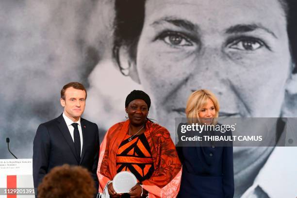 Cameroonian activist Aissa Doumara Ngatansou poses for a photo with French President Emmanuel Macron and his wife Brigitte Macron after she received...