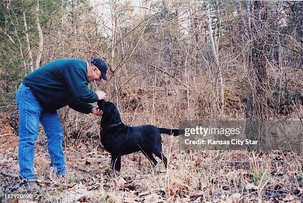 Rural Missouri landowner John Lindsey plays with his black Labrador on Mark Twain National Forest Land adjoining his rural residence southeast of...