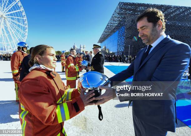 French Interior Minister Christophe Castaner gives an helmet to a new recruit during the ceremony of the 80th anniversary of the naval firefighters...