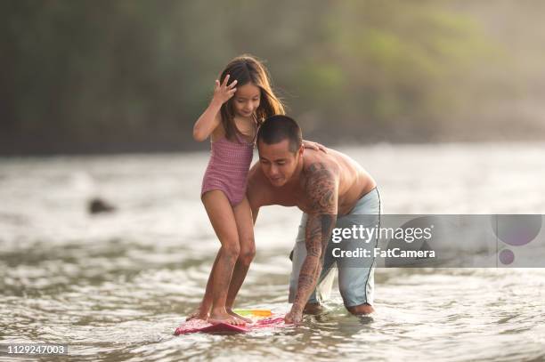 eurasische vater lehrt seinen lilttle mädchen surfen - hawaii fun stock-fotos und bilder