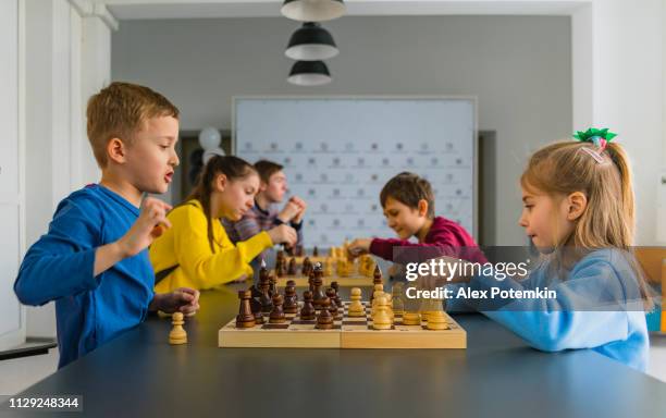 kids of different ages, boys and girls, playing chess on the tournament in the chess club - chess championship stock pictures, royalty-free photos & images