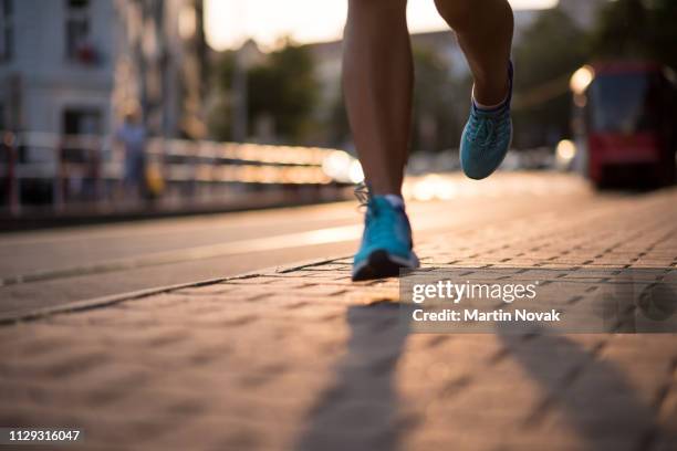 closeup of athlete feet in running shoes - blurred running sunset stock-fotos und bilder