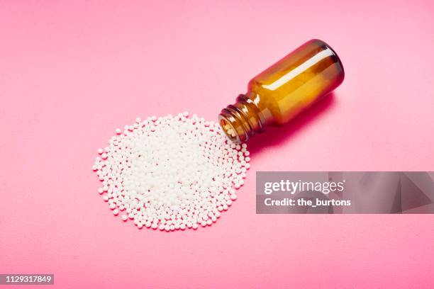 little bottle with globules on pink background - homeopathic medicine stock-fotos und bilder