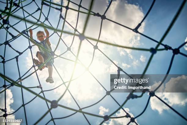 little boy climbing a giant climbing web on modern playground - kids climbing stock pictures, royalty-free photos & images