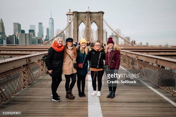 gruppe frauen auf der brooklyn bridge - new york tourist stock-fotos und bilder