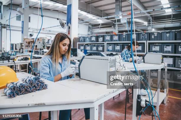 industrial worker woman working together with manufacturing equipment in a factory - manual assembly stock pictures, royalty-free photos & images