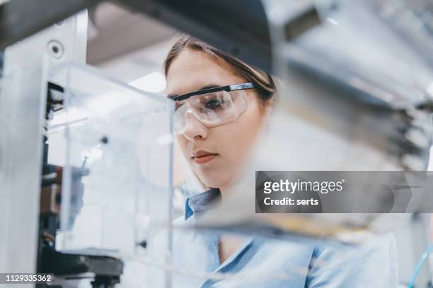 kvinnliga industriarbetare som arbetar med utrustning i en fabrik för tillverkning - science bildbanksfoton och bilder