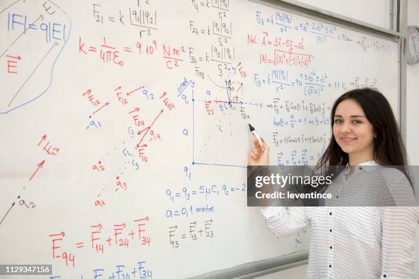 studente universitario che risolve i problemi davanti alla lavagna - matematico foto e immagini stock