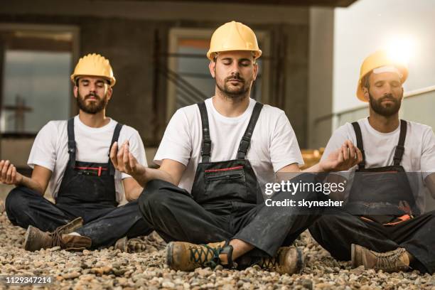 team van handarbeiders mediteren op een terras van een bouwterrein. - leaving work stockfoto's en -beelden
