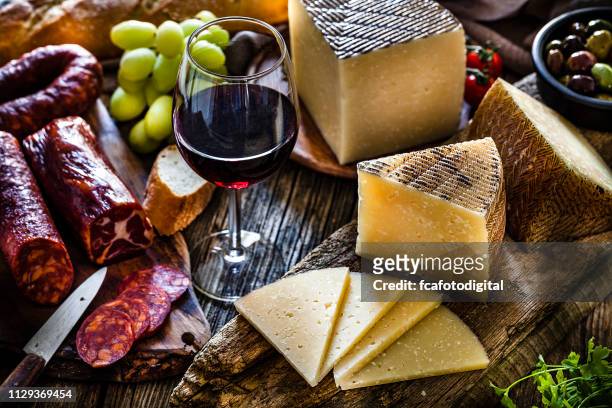 spanische küche: manchego käse, spanische chorizo und rotwein auf rustikalen holztisch - spanische kultur stock-fotos und bilder