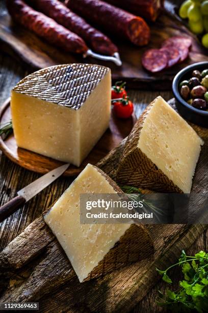 comida española: queso manchego, chorizo español y aceitunas sobre mesa rústica de madera - queso manchego fotografías e imágenes de stock