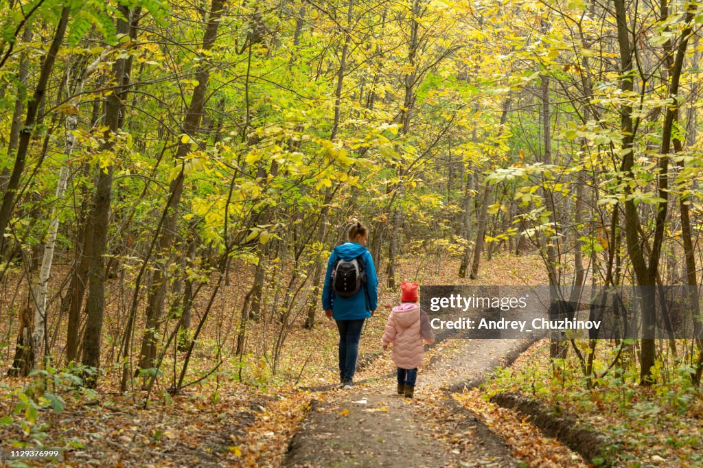Madre e hija están caminando en el bosque de otoño