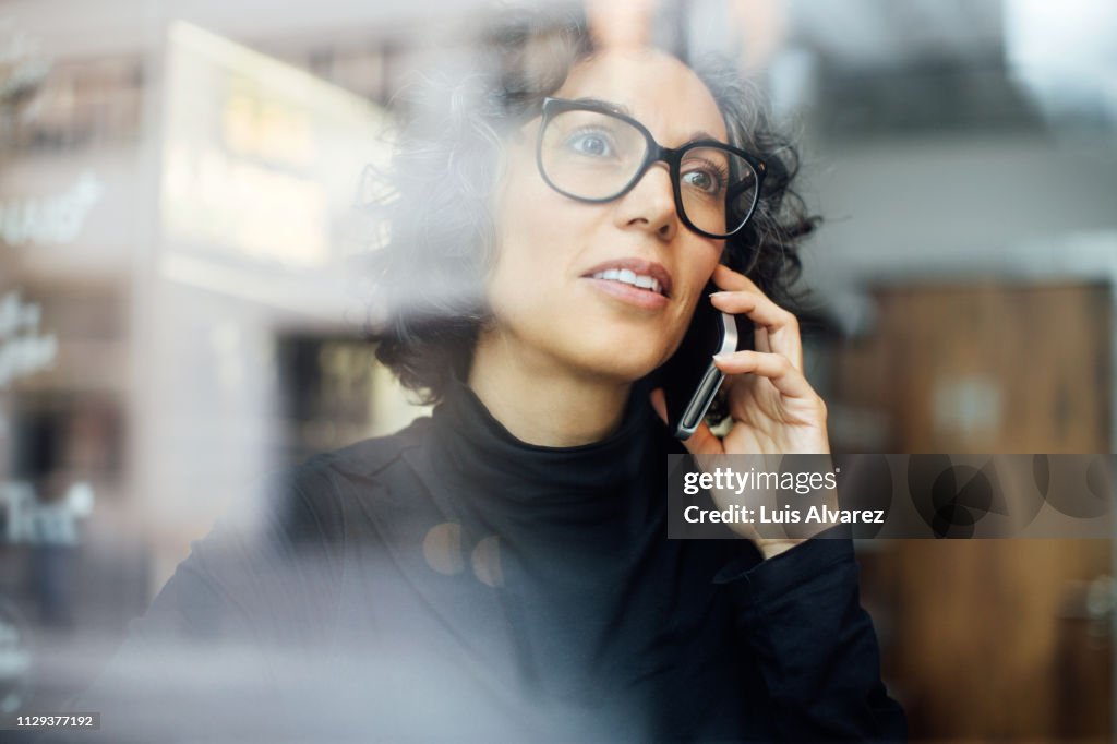 Mature woman inside a cafe talking on mobile phone