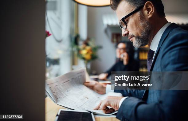 mid adult business professional reading newspaper in cafe - article of furniture stock pictures, royalty-free photos & images