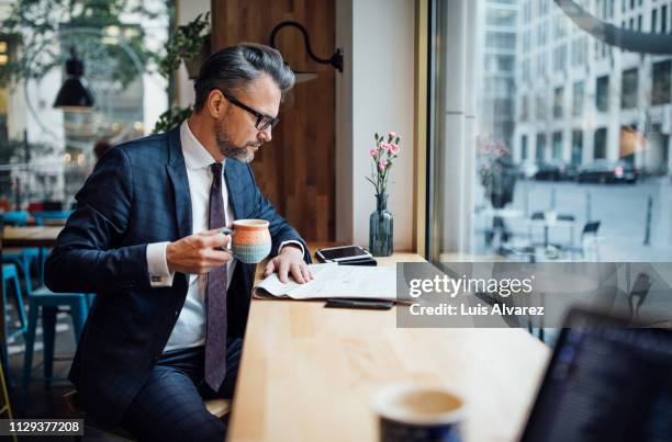 businessman drinking coffee and reading newspaper at cafe - newspaper article stock pictures, royalty-free photos & images